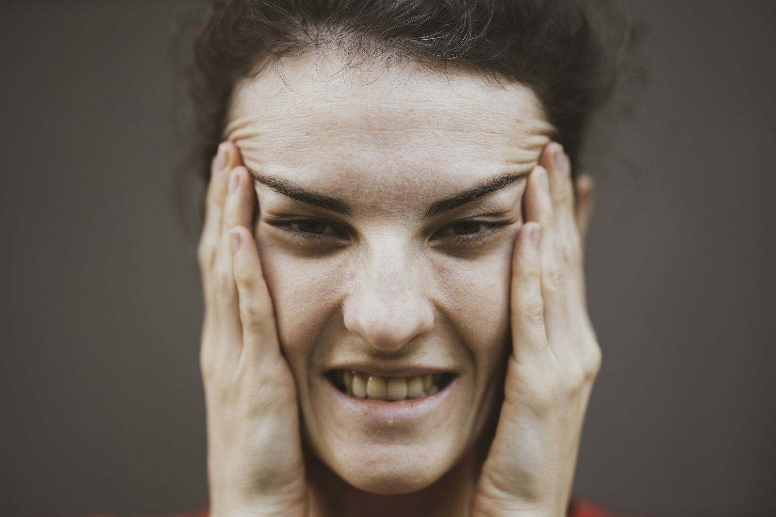 Woman in red shirt holding her face