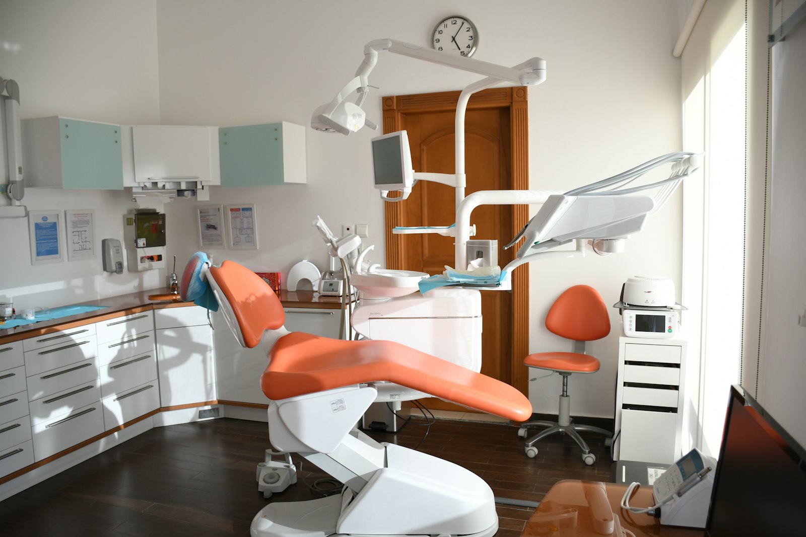 An orange dental chair with medical equipment in a bright clinical office