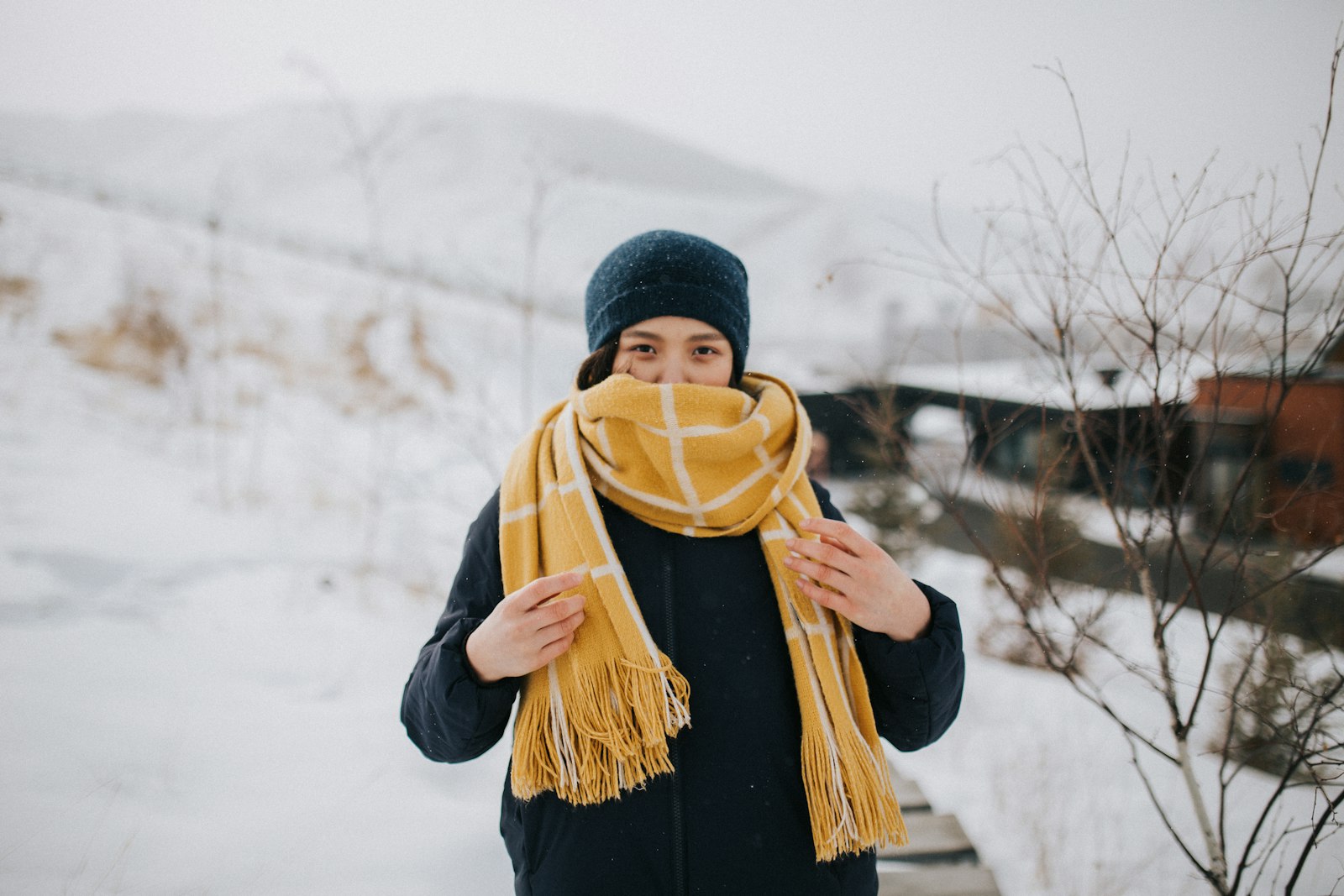 Woman in black knit cap and black jacket standing on snow covered ground during daytime